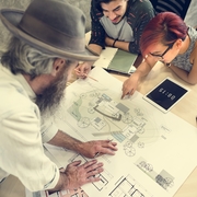 Three people reviewing architectural plans on a table.