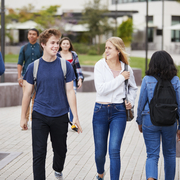 Students walking together on campus with backpacks and casual outfits.