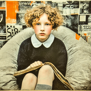 girl sits in a beanbag with newspaper in lap surrounded by collage