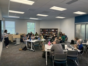 image of faculty participating in UMKC's First Semester Experience in a conference room, sitting at tables with a presenter at the front of the room
