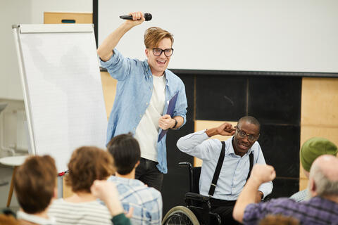 group of college students with one student up front with a microphone by chart paper
