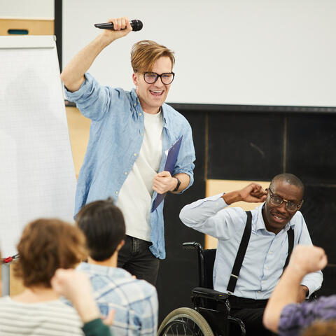 group of college students with one student up front with a microphone by chart paper