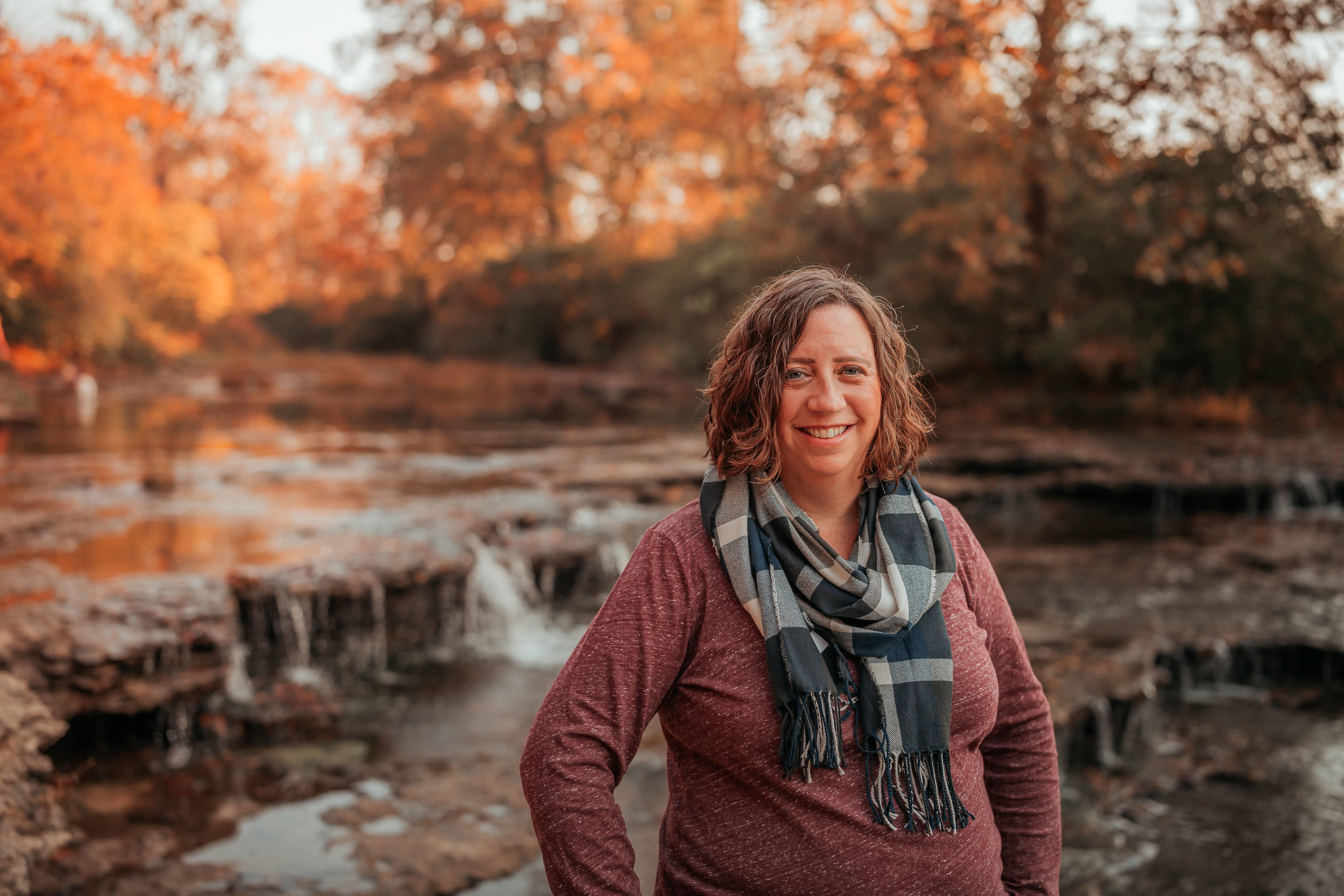 Dr. Tiffani Riggers-Piehl standing in front of a stream and trees.