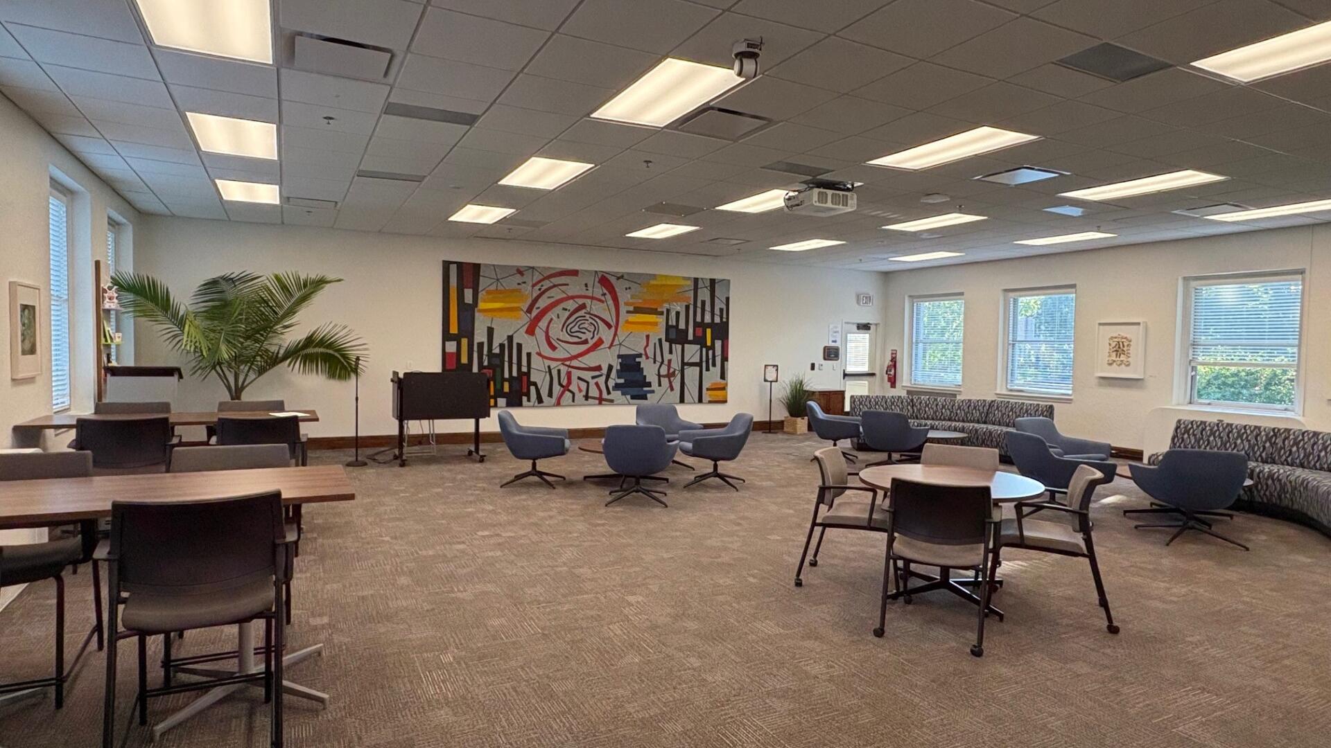 The Faculty Commons, with a mural at the far wall and tables and chairs in the foreground