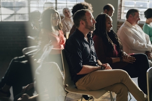 researchers and students facing toward speaker with light streaming in